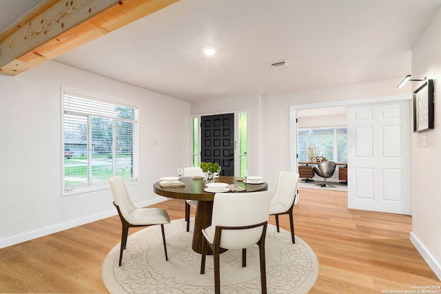 dining room featuring beamed ceiling, a healthy amount of sunlight, and light wood-type flooring