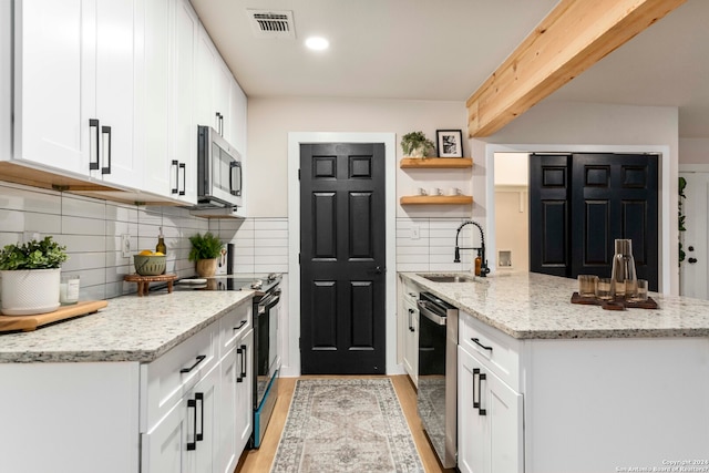 kitchen featuring stainless steel appliances, light hardwood / wood-style flooring, white cabinetry, backsplash, and sink