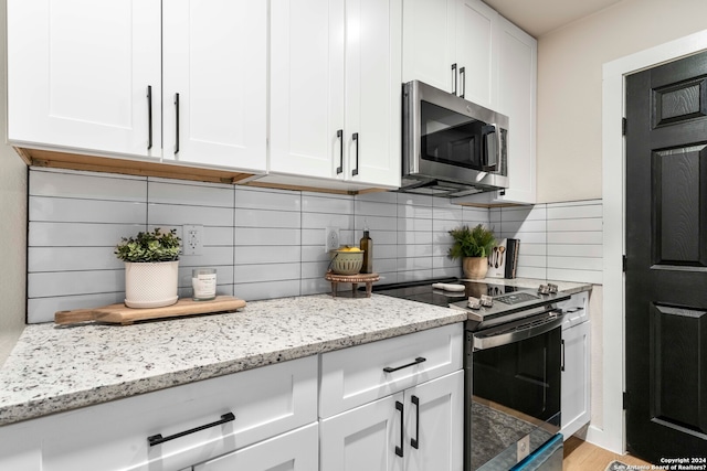 kitchen with backsplash, light hardwood / wood-style floors, white cabinets, and electric range oven