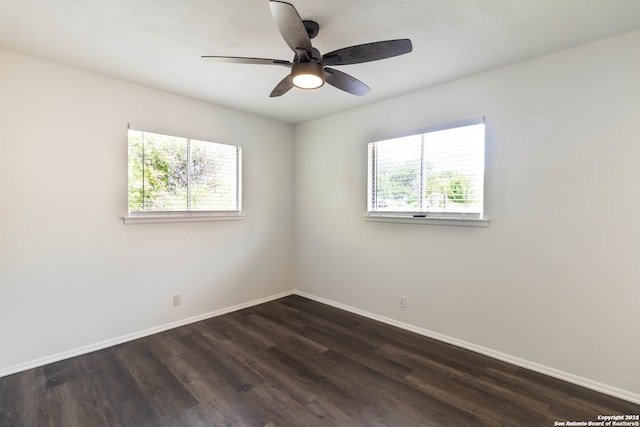 empty room featuring ceiling fan, dark wood-type flooring, and a wealth of natural light