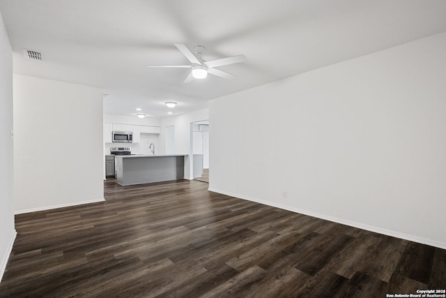 unfurnished living room featuring ceiling fan and dark hardwood / wood-style flooring