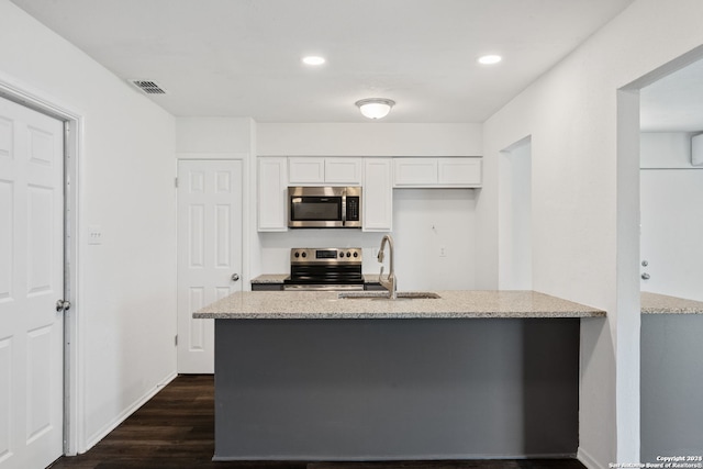 kitchen with light stone countertops, white cabinetry, dark hardwood / wood-style floors, appliances with stainless steel finishes, and sink