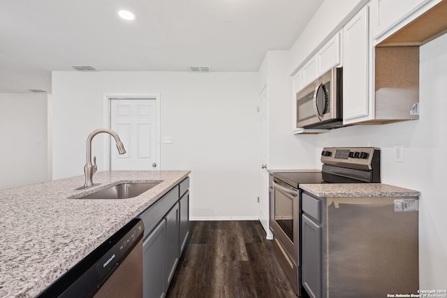 kitchen featuring stainless steel appliances, light stone countertops, dark wood-type flooring, white cabinetry, and sink