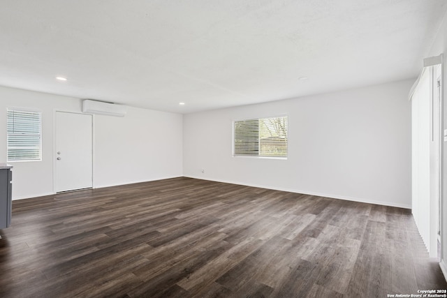 spare room with dark hardwood / wood-style floors and an AC wall unit