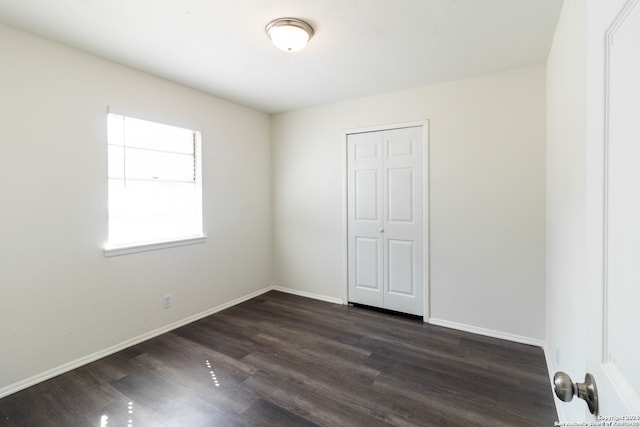 unfurnished bedroom with a closet and dark hardwood / wood-style floors