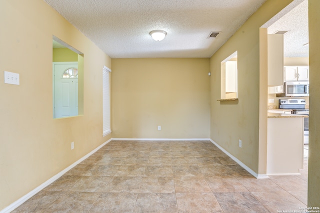 spare room with a textured ceiling and light tile floors