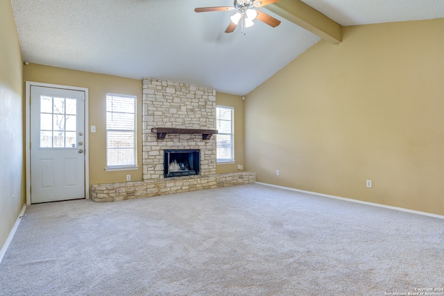 unfurnished living room featuring ceiling fan, light colored carpet, a stone fireplace, and vaulted ceiling with beams