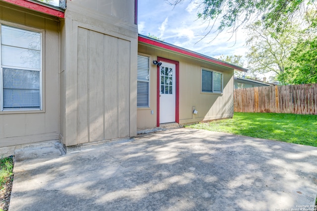 view of exterior entry featuring a lawn and a patio area