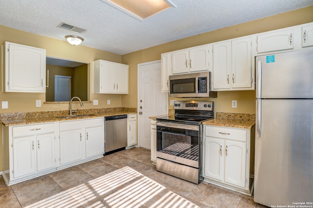 kitchen featuring white cabinets, light stone countertops, appliances with stainless steel finishes, and sink