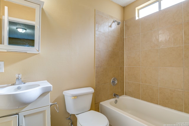 full bathroom with vanity, a textured ceiling, toilet, and tiled shower / bath