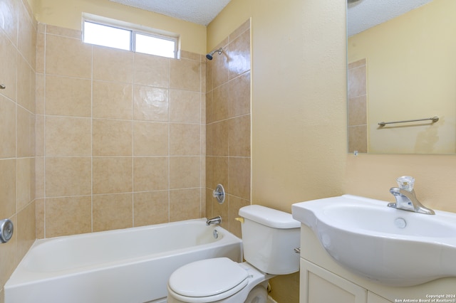 full bathroom with tiled shower / bath, toilet, vanity, and a textured ceiling