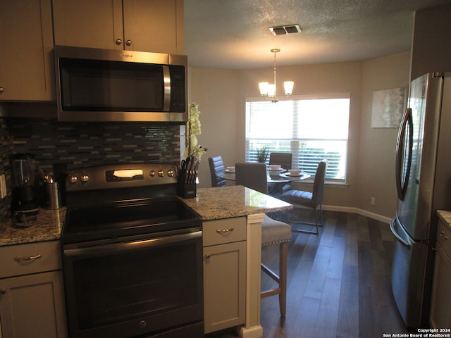 kitchen featuring an inviting chandelier, tasteful backsplash, light stone counters, and stainless steel appliances