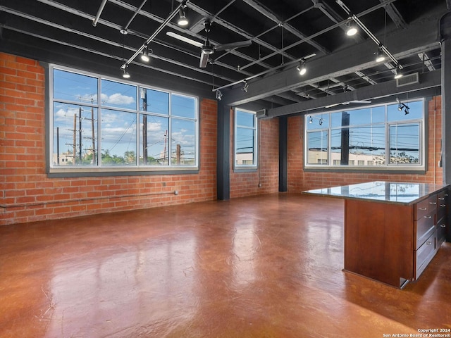 empty room with finished concrete flooring, brick wall, visible vents, and rail lighting