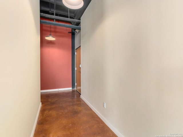 hall featuring finished concrete flooring and baseboards