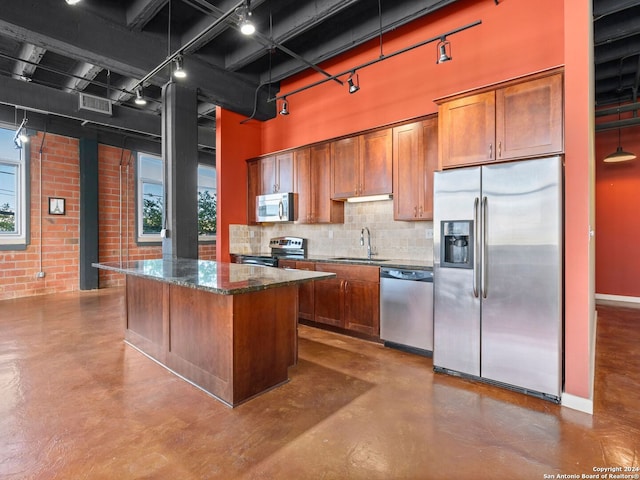 kitchen featuring dark stone counters, a kitchen island, stainless steel appliances, backsplash, and sink