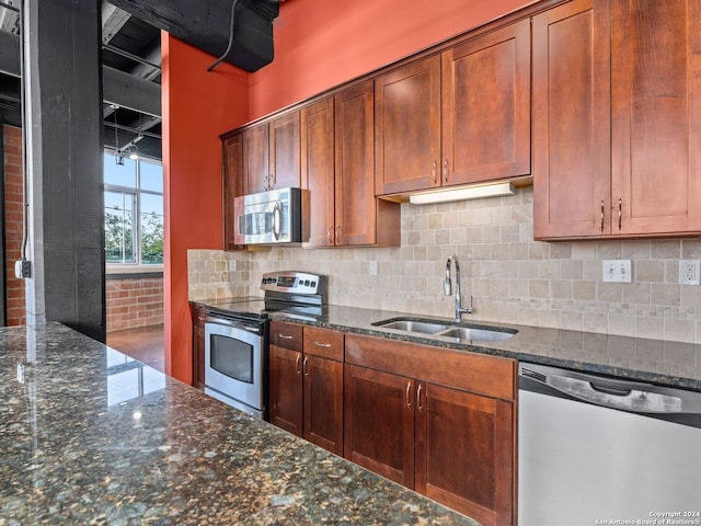 kitchen featuring appliances with stainless steel finishes, sink, tasteful backsplash, and dark stone counters