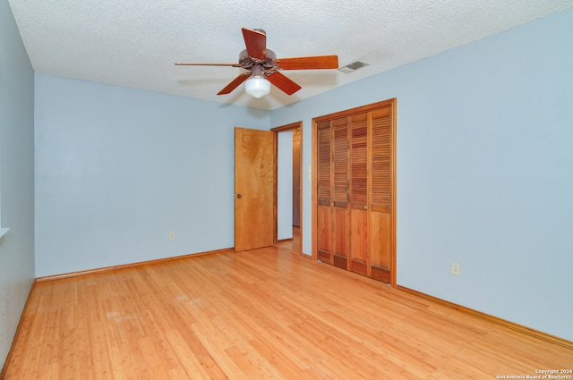 unfurnished bedroom featuring a textured ceiling, a closet, light wood-type flooring, and ceiling fan