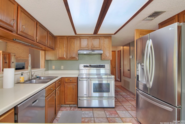 kitchen featuring appliances with stainless steel finishes, sink, a textured ceiling, and light tile floors