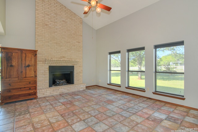 unfurnished living room with tile flooring, ceiling fan, a brick fireplace, brick wall, and high vaulted ceiling