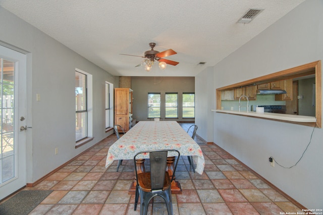 tiled dining area featuring sink, a textured ceiling, plenty of natural light, and ceiling fan