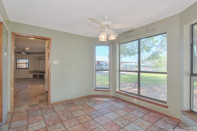 spare room with tile flooring, ceiling fan, and a textured ceiling