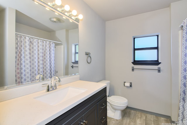 bathroom featuring vanity with extensive cabinet space, hardwood / wood-style flooring, and toilet