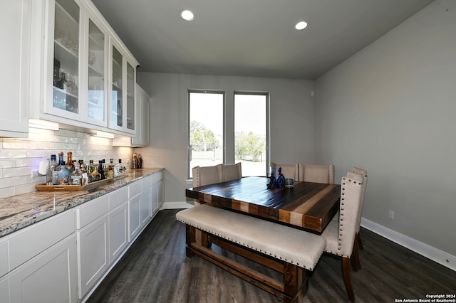 dining space featuring dark wood-type flooring and bar