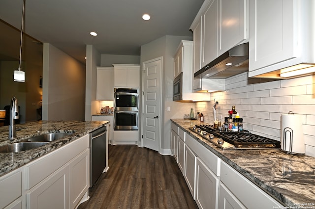 kitchen with sink, dark stone counters, appliances with stainless steel finishes, wall chimney exhaust hood, and white cabinetry