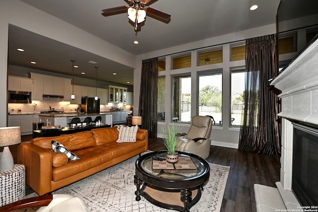 living room with hardwood / wood-style floors, ceiling fan, and a tile fireplace