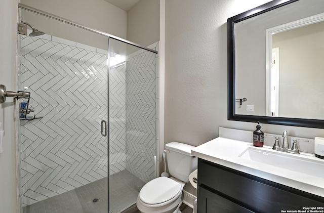 bathroom with toilet, vanity, and a shower with door