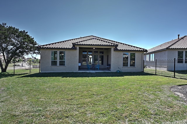 back of property with a lawn, a patio area, and french doors