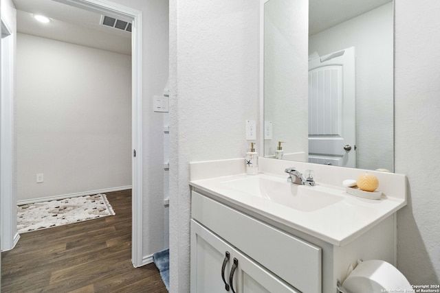 bathroom with toilet, vanity with extensive cabinet space, and wood-type flooring