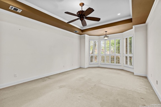 carpeted empty room featuring a raised ceiling, ceiling fan, and ornamental molding