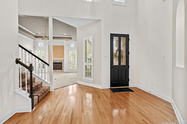 entryway featuring a high ceiling, ceiling fan, light hardwood / wood-style flooring, and a fireplace