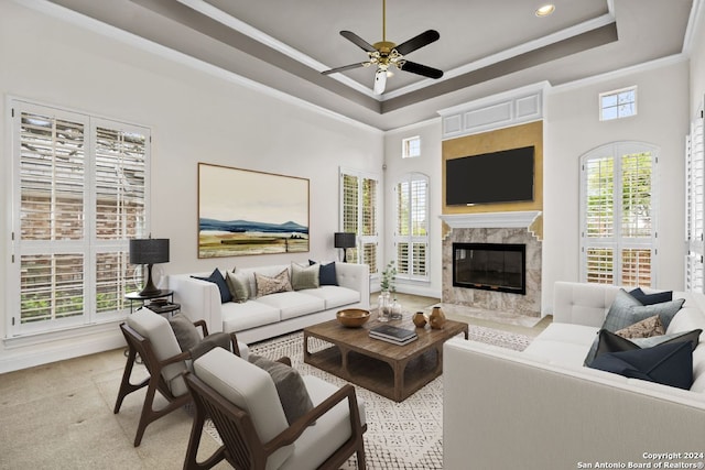 living room with ceiling fan, a premium fireplace, a raised ceiling, a towering ceiling, and ornamental molding