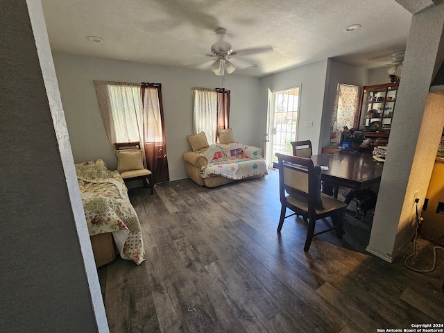 living room featuring ceiling fan, a textured ceiling, and dark hardwood / wood-style flooring