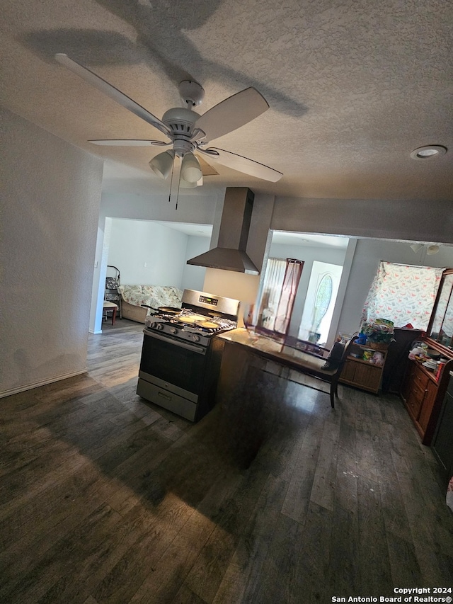 kitchen with gas stove, dark hardwood / wood-style floors, wall chimney exhaust hood, ceiling fan, and a textured ceiling