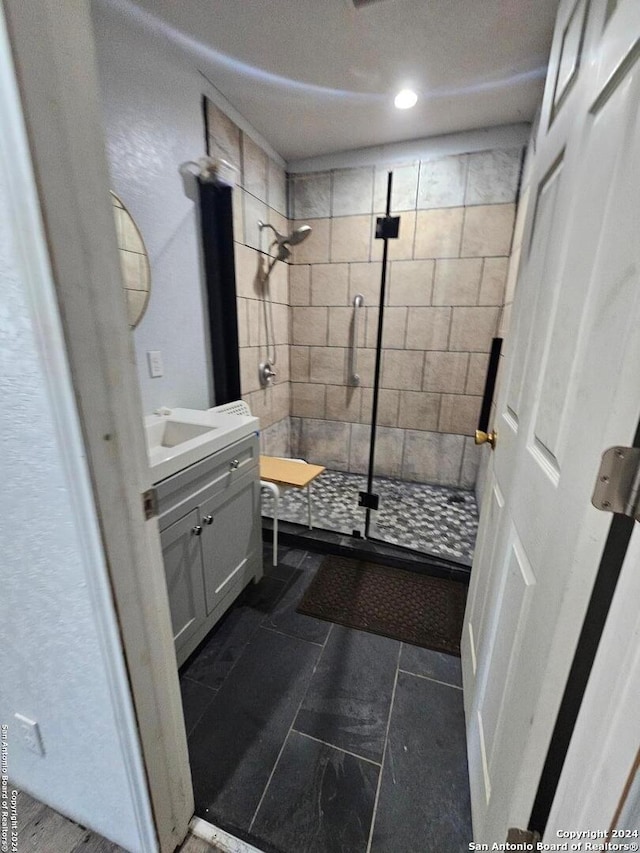 bathroom with tile flooring, tiled shower, and vanity