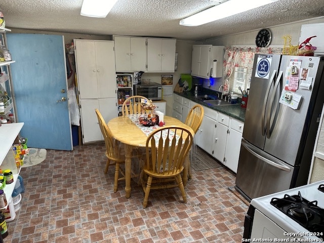 kitchen featuring stainless steel appliances, a textured ceiling, white cabinetry, and sink