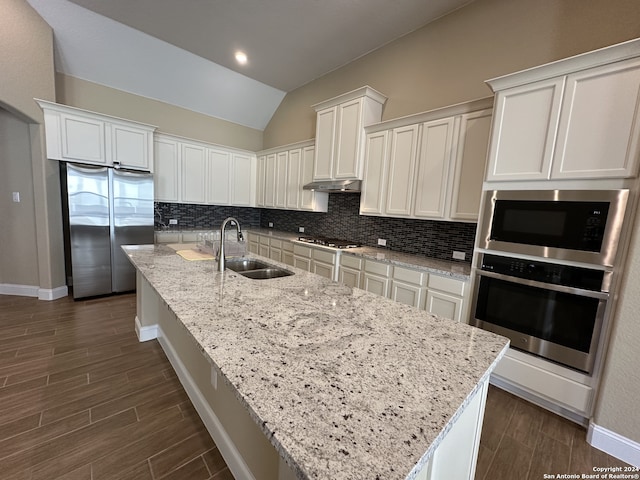 kitchen with dark wood-type flooring, white cabinets, sink, vaulted ceiling, and stainless steel appliances