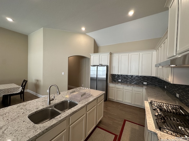 kitchen with light stone counters, vaulted ceiling, dark hardwood / wood-style floors, and sink