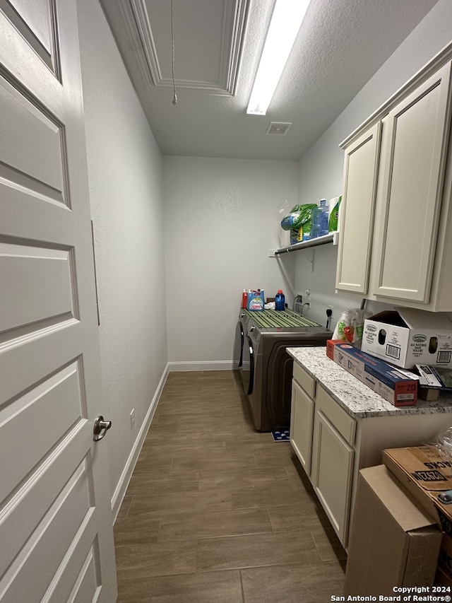 clothes washing area featuring hardwood / wood-style floors, cabinets, a textured ceiling, and washing machine and clothes dryer