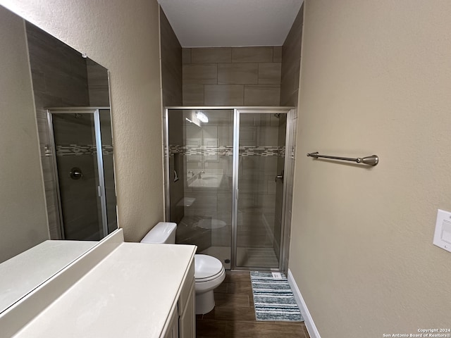 bathroom with a shower with door, vanity, wood-type flooring, and toilet