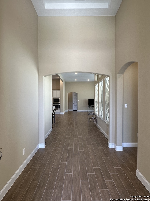 hallway with a towering ceiling and dark hardwood / wood-style flooring