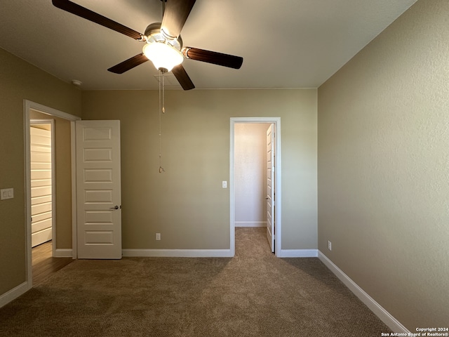 unfurnished bedroom featuring a walk in closet, ceiling fan, a closet, and carpet