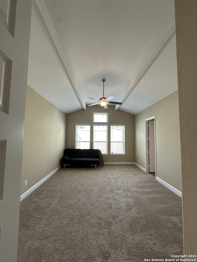 unfurnished room featuring carpet, a textured ceiling, vaulted ceiling with beams, and ceiling fan