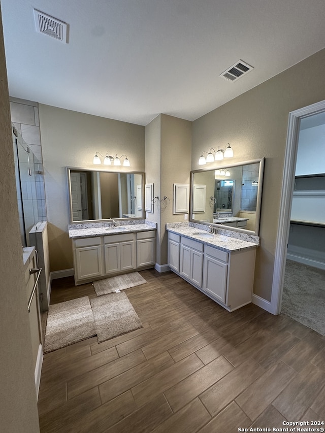 bathroom with a tile shower, vanity, and wood-type flooring