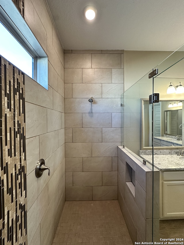 bathroom featuring vanity, a textured ceiling, and tiled shower