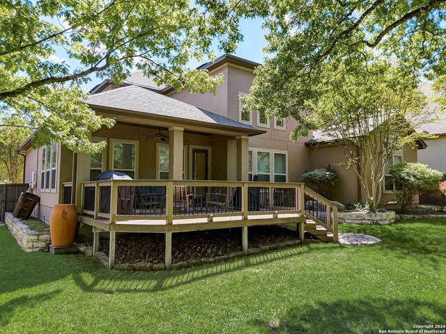 back of property featuring ceiling fan, a wooden deck, and a lawn