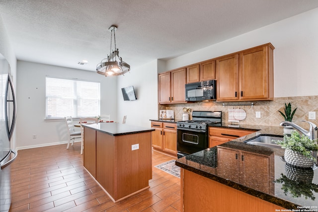 kitchen with a kitchen island, decorative light fixtures, tasteful backsplash, black appliances, and dark stone countertops